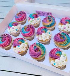 a box filled with lots of colorful cupcakes