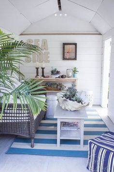 a living room filled with furniture and plants on top of a blue and white striped rug