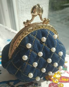 a small purse with pearls on it sitting on a table next to an open window