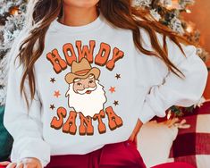 Howdy Santa Sweatshirt Retro Christmas Crewneck Western Clothes Country Christmas Trendy Oversized Xmas Sweater Preppy Clothes Yeehaw PERFECT GIFT for friends, family, and coworkers. Order affordable, high-quality, personalized t-shirts. Carefully hand-printed using the latest DTF Printing Technology and High-Quality inks. THANKS FOR CHOOSING SNOWDROPTEE! WHAT SIZE FITS ME BEST SIZE CHART - PLEASE, SCROLL THROUGH THE PHOTOS. MEASUREMENTS FOR CLOTHING TYPES AND SIZES ARE LISTED AS WELL. THESE ARE Vintage Christmas Shirt, Santa Graphic, Christmas Sweater Funny, Western Sweatshirts, Santa Sweatshirt, Cute Christmas Shirts, Retro Santa, Ugly Christmas Sweater Funny, Ugly Christmas Sweater Party