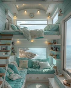 a room with bunk beds and blue pillows on the floor next to the ocean in front of a window