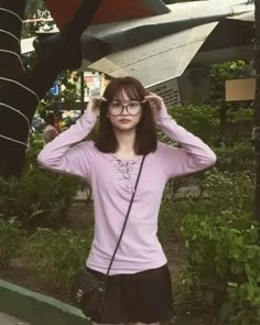 a young woman wearing glasses and holding her hair in front of an airplane wing sculpture