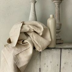 two vases and a cloth on top of an old dresser