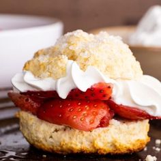 a strawberry shortcake with whipped cream and strawberries on top is ready to be eaten