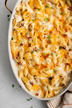 a casserole dish with chicken, cheese and green onions in it on a white surface