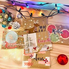 some christmas cards are laying on a table with lights in the background and decorations around them