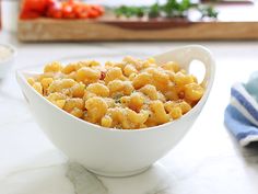 a white bowl filled with macaroni and cheese on top of a marble counter