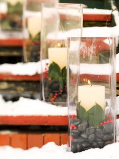 candles are sitting in clear vases on the snow