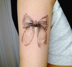 a woman's arm with a bow tattoo on it