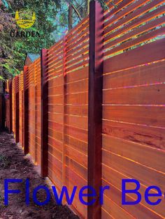 an image of a wooden fence with the words flower bed on it and trees in the background