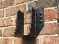 a brick wall with two black brackets attached to it's side and one is on the other side