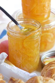 jars filled with orange marmalade sitting next to croissants