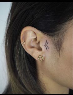 a woman's ear with two piercings on top of her ears and one behind the ear