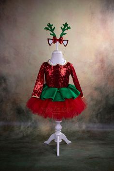 a red and green christmas dress on a mannequin headpiece with reindeer antlers