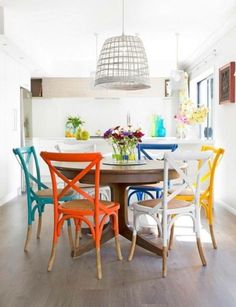 a dining room table with colorful chairs around it