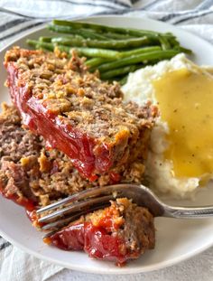 meatloaf, mashed potatoes and green beans on a plate with a fork