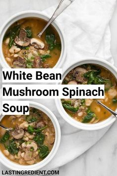 three bowls of white bean mushroom spinach soup with spoons on a marble surface