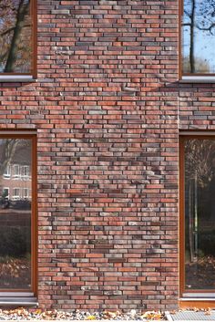 a red brick building with two windows on each side and trees in the back ground