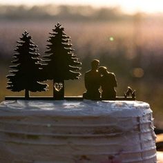 the cake is decorated with figurines of people and trees