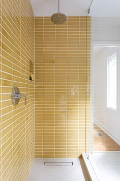 a bathroom with yellow tiles on the wall and shower head in the corner, along with a white bathtub next to it