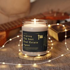 a candle sitting on top of a wooden table next to a string of lights and a guitar