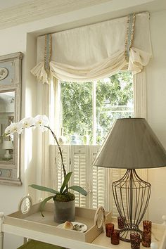 an image of a room with a lamp and pictures on the window sill in it