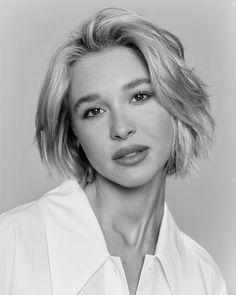 a black and white photo of a woman with short blonde hair wearing a collared shirt