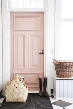 a black and white checkered floor next to a pink door with a basket on it