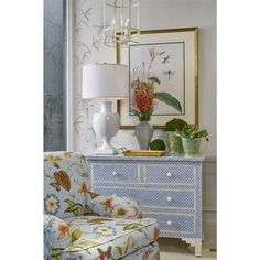 a blue dresser with flowers on it and a white lamp next to it in a living room