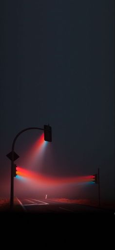 a traffic light sitting on the side of a road next to a street sign at night