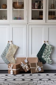 three christmas stockings tied up next to each other in front of white cupboards with glass doors