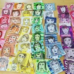 many different colored paper pictures on a wooden table with one woman's face in the middle