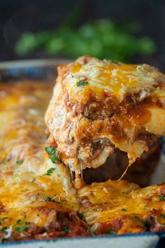 a piece of lasagna being lifted from a casserole dish with meat and cheese