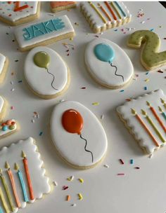 decorated birthday cookies arranged on a table with confetti and candles in the shape of balloons