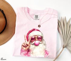 Comfort Colors Shirt, Pink Santa Shirt, Blowing Bubble Christmas Shirts, Santa with Sunglasses Christmas Tee, Santa Christmas Shirt Welcome to Opia Apparel. Here you will find personalized t-shirts for your friends and family that will make you smile. We want to make everyone smile with our cute , stylish and trendy graphic T-shirts. We can assured you this shirt will be perfect gift whether you will buy it yourself or for someone else. ✷ About Us ✷ This new business was founded by a small family. Your t-shirt will be made with love. Thank you for choosing us. ✷ Sizing and Color Guidelines✷ Unisex t-shirt size: S | M | L | XL | 2XL | 3XL We use Comfort Colors Heavyweight brand t-shirts for all listings where Comfort Colors is mentioned in the title. These shirts are unisex and designed to Pink Christmas Shirt, Bubble Christmas, Pink Santa, Santa Sweatshirt, Santa Shirt, Christmas Tshirt, Santa Shirts, Funny Christmas Shirts, Family Christmas Shirts