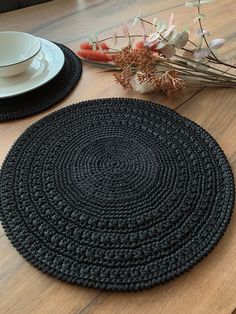 two place mats on top of a wooden table with flowers in the middle and white plates next to them