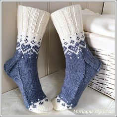 the legs of someone wearing socks with blue and white knitted designs on them, sitting next to a wicker basket