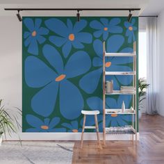 a blue and green flower wall mural in a room with wooden flooring, white chair and book shelf