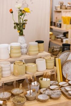 a table filled with pottery and vases on top of wooden shelves next to each other