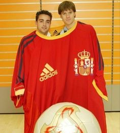 two young men standing next to each other with a soccer ball in front of them