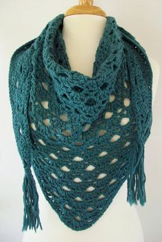 a green crocheted shawl is on a mannequin