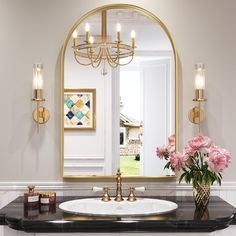 a bathroom with a sink, mirror and flowers in vases on the counter top