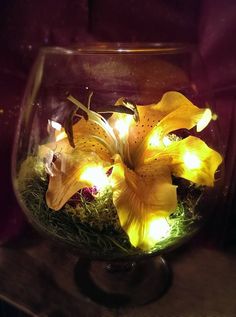 a glass bowl filled with yellow flowers on top of a table