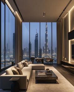 a living room filled with furniture and large windows overlooking the cityscape at night