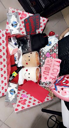 a pile of valentine's day gifts sitting on top of a floor next to a table