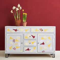 a painted dresser with flowers and plants on top