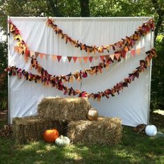 hay bales and pumpkins are arranged in front of a white backdrop with bunting