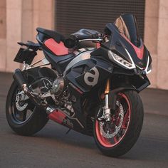 a motorcycle parked in front of a building on a street with red and black rims