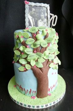 a birthday cake decorated with a tree and photo frame on top, sitting on a table