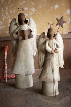 two angel figurines are standing next to each other with books in their hands